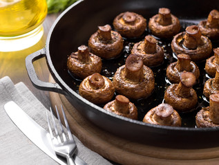 Homemade baked mushrooms in the pan on a cutting board.