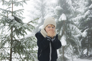 a boy in snowy winter forest warms his arms
