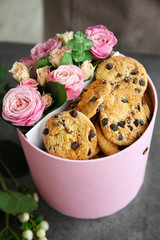 Close up view of box with beautiful flowers and cookies on dark textured table