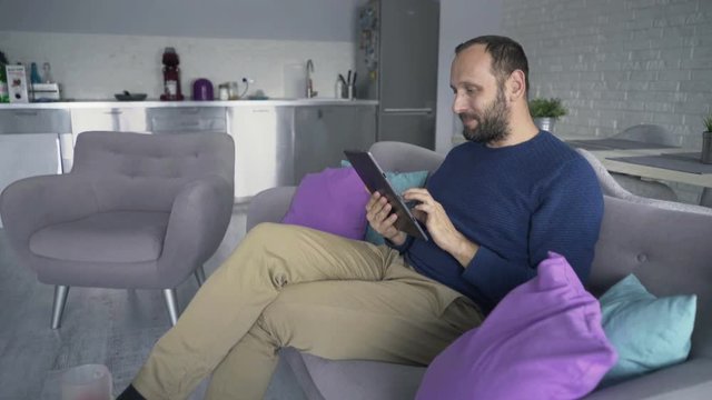 Young man using tablet computer sitting on sofa at home
