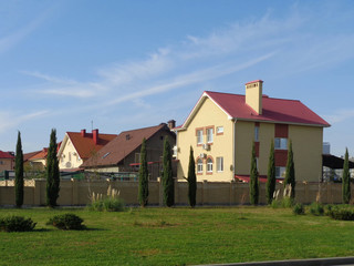 Новые коттеджи за кирпичной стеной, зеленая лужайка