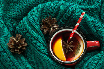 Christmas and winter traditional hot beverage. Mulled wine in red mug with spice wrapped in warm green scandinavian sweater. © svetlana_cherruty