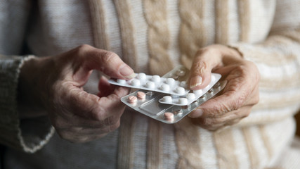 closeup of old female hands holding pills