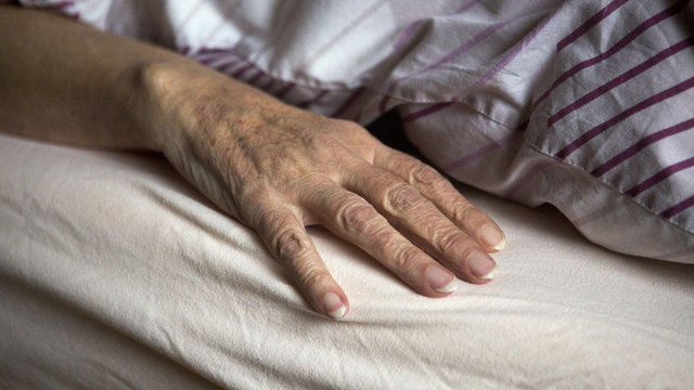 closeup of old female hand in bed