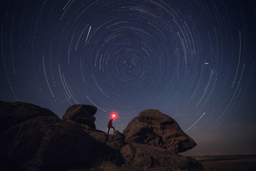 Rock and man silhouette over star tracks