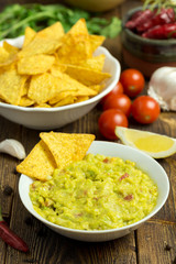 Guacamole in white bowl on natural wooden desk.