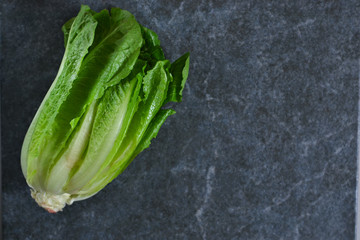 Romaine lettuce on black marble background. View from above.