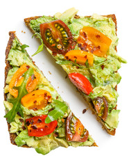 Slice of rye bread with avocado, colorful tomatoes and aragula leaves
