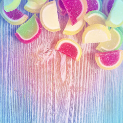 Sweet tasty vibrant candies, top view. Wooden background, copyspace