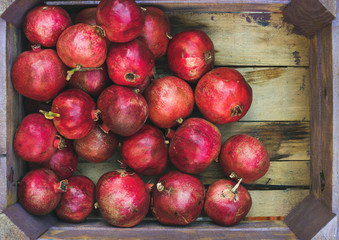 Fototapeta na wymiar Turkish ripe red pomegranates in rustic wooden box, top view, copy space, horizontal composition