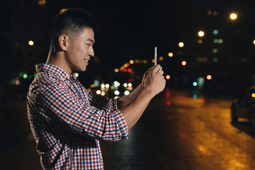 Young asian man with headphones taking a picture.