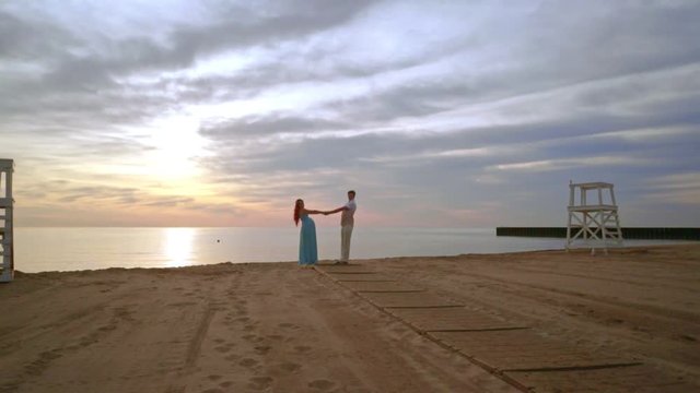 Pregnant couple dancing on sea beach at sunset. Happy couple. Expecting parents concept. Love couple having fun. Couple beach sunset. Couple beach happy. Love couple beach. Dancing couple