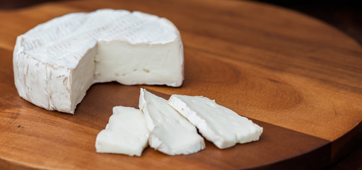 Fototapeta na wymiar Brie or camembert cheese cut on a cheeseboard