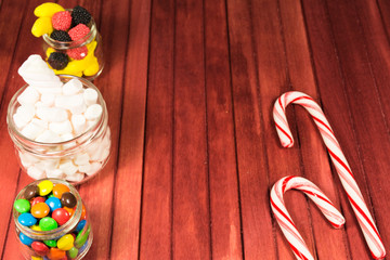 Different color candies on red wooden background