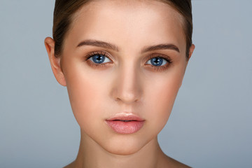 Fototapeta premium Close-up portrait of sexy young woman with beautiful blue eyes. Woman beauty face portrait with healthy skin. Portrait of beautiful young woman looking at camera. Natural beauty concept