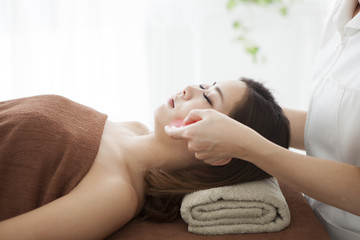 Obraz na płótnie Canvas Woman is massaged face with guasha