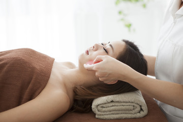 Woman is massaged face with guasha