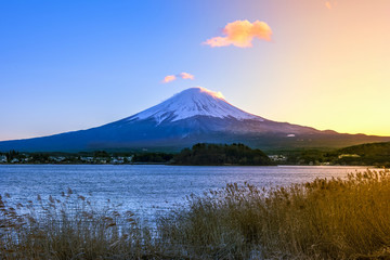 Japan, Fuji mountain, Kawaguchiko lake in autumn evening, With warm sunlight effect created reflection highlight shadow at the mountain, land, lake and building (blur foreground)