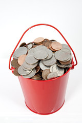 Red metal pail filled with US coins. Vertical. © Noel