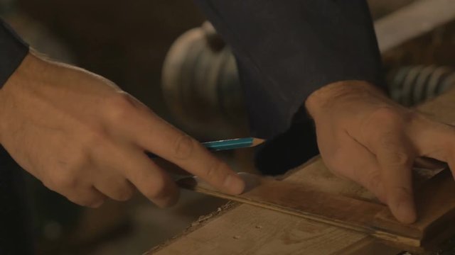 master carpenter makes basting on the Board with a pencil, draws, craftsman work tool in the workshop.