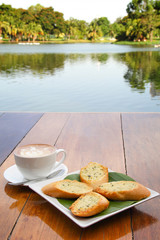 Cup of latte coffee and homemade garlic herb bread on table