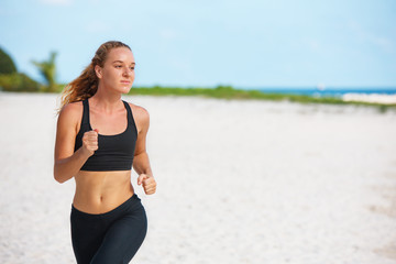 young fitness woman running at beach