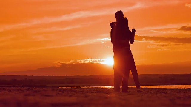 couple dancing a slow dance in sunset sun silhouettes, Valentine's Day a man and a woman