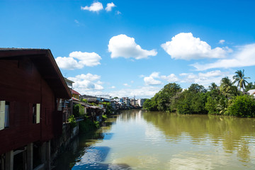Urban canal village under blue sky and clouds, Thailand