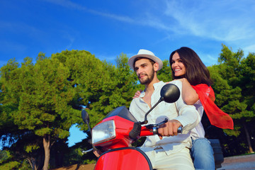 Fototapeta na wymiar Beautiful young couple in love enjoying and having fun riding on a scooter