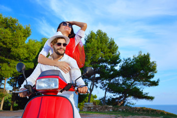 Beautiful young couple in love enjoying and having fun riding on a scooter