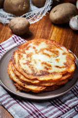 Stack of potato pancakes on a wooden table. In the background po