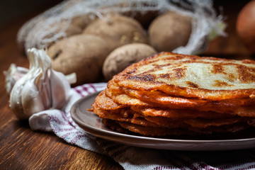 Stack of potato pancakes on a wooden table. In the background po