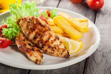 Grilled chicken breasts served with fries and fresh salad