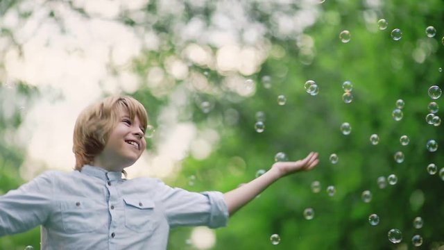 Smiling boy with soap bubbles in park