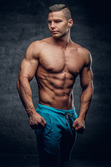 Fototapeta premium Shirtless muscular male in contrast illumination.