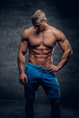 Obraz na płótnie Canvas Shirtless muscular male in contrast illumination.