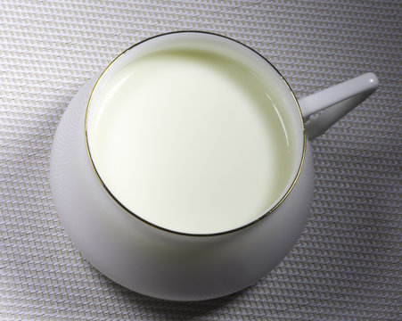  Milk in white porcelain cup. Square close up shot. Hard light.