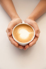 Hot coffee with heart shape on top in woman hands