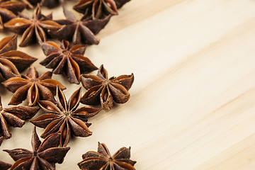 Anise star close up on wooden beige background. Decorative border of star anise spice on wood board.