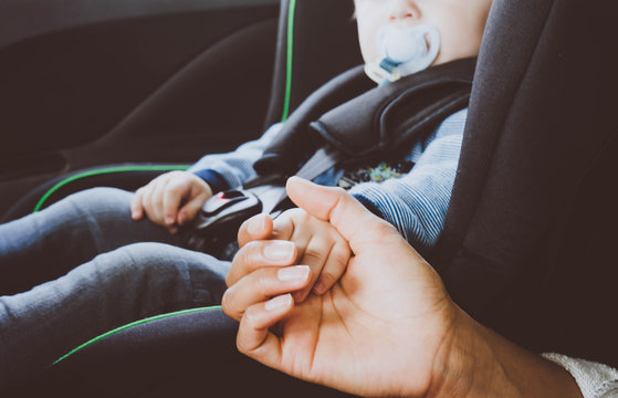 Frau hält die Hand eines Kleinkinds im Auto 