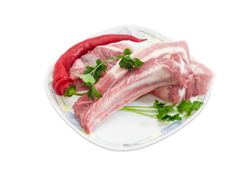 Uncooked pork ribs, chilli and parsley twigs on dish