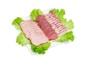 Sliced different prepared pork on lettuce on square white dish