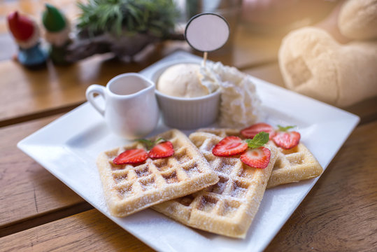 Strawberry waffle and honey with ice cream on wooden table, selective focus, lights effects.