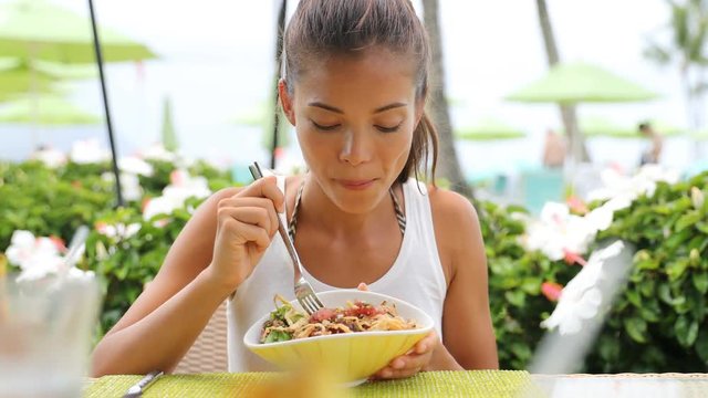 Asian woman eating a fresh raw tuna dish, hawaiian local food poke bowl, at outdoor restaurant table during summer travel vacation. Hawaii poke bowl food plate. Ahi tuna hawaiian cuisine. 59.94 FPS.