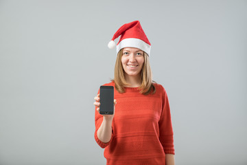 Young  woman with Santa hat showing smartphone