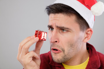 Closeup portrait unhappy, upset man holding small red gift