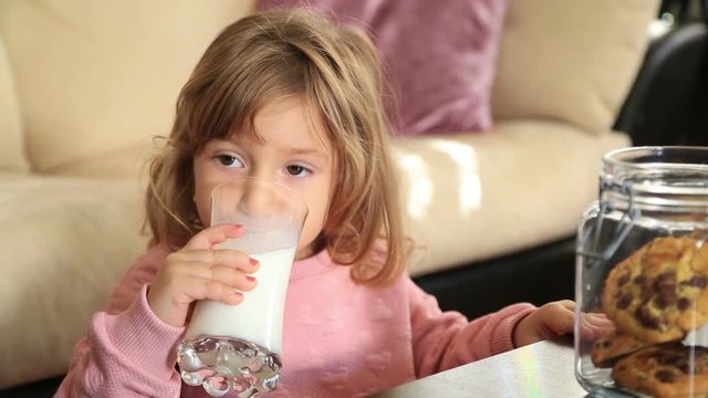Portrait of a adorable smiling blond little girl with long hair with a glass of milk
