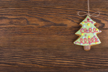 Gingerbread cookies hanging over wooden background. Christmas decorations top view with copy space. Prepare for xmas eve or other winter holidays
