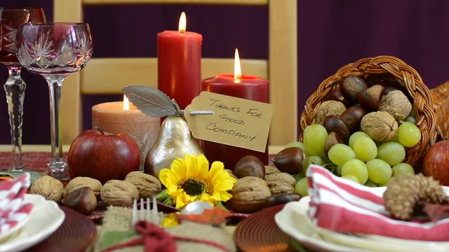 Traditional Thanksgiving table with place settings and cornucopia centerpiece in colorful rustic style, static closeup.