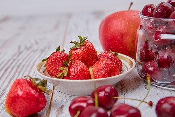 Cherry in glass jar on and Strawberry on plate rustic table